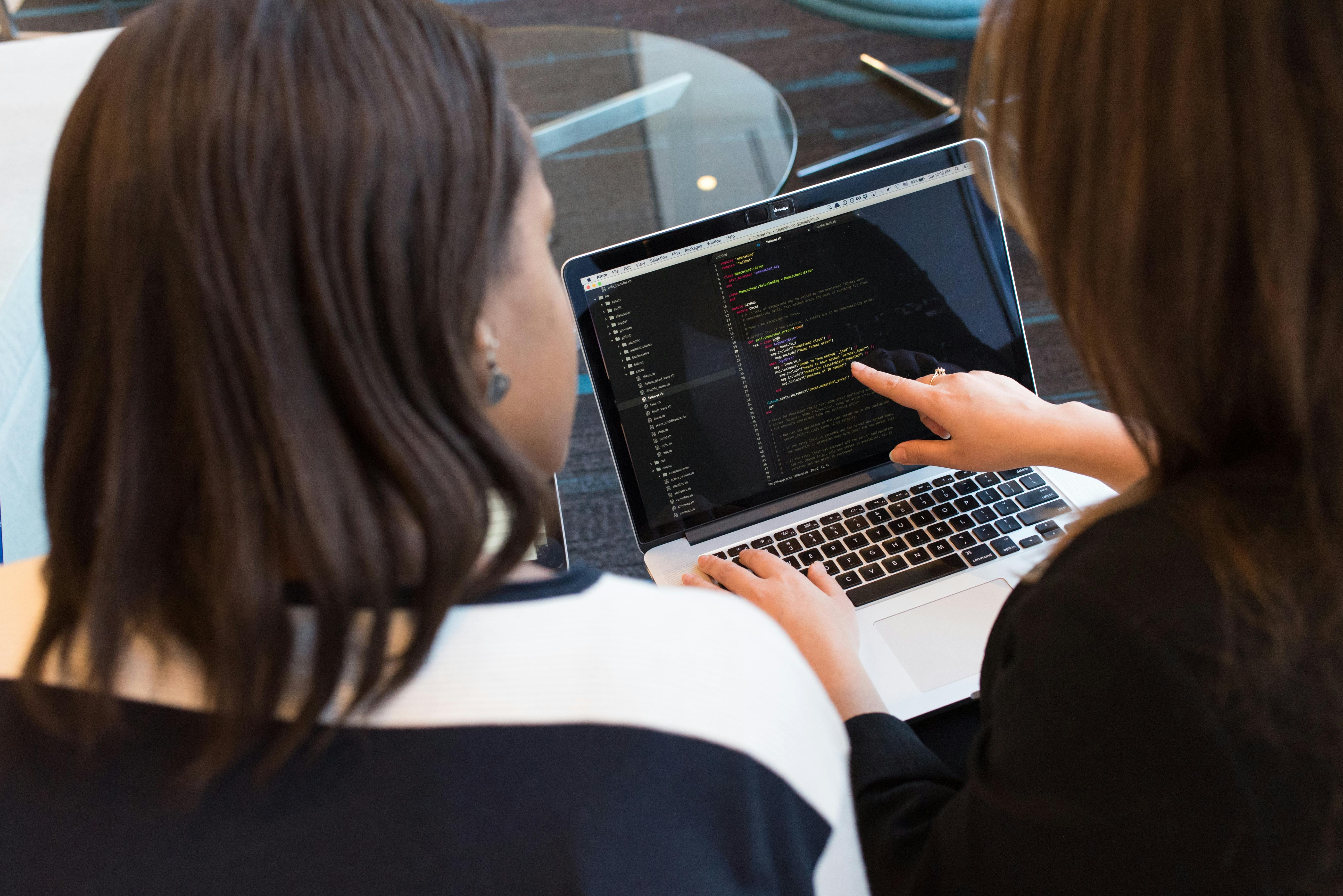 Two women reviewing code on a laptop